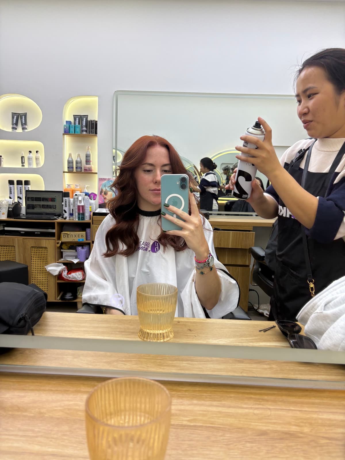 A happy client smiling while looking at her new haircut in the mirror